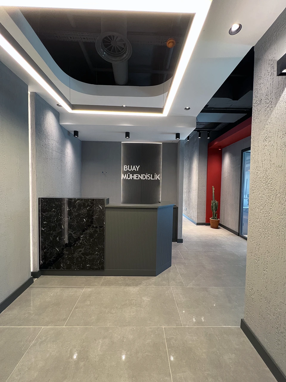 Kurumsal ofis resepsiyon — logo duvarı, siyah mermer banko ve LED tavan