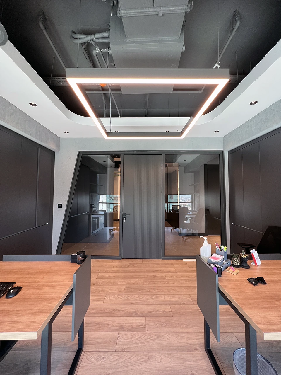 Açık ofis çalışma alanı — ahşap masalar ve dikdörtgen LED aydınlatma