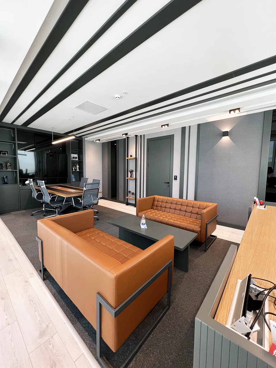 Yönetici odası oturma alanı — taba deri koltuklar ve çizgili tavan detayı