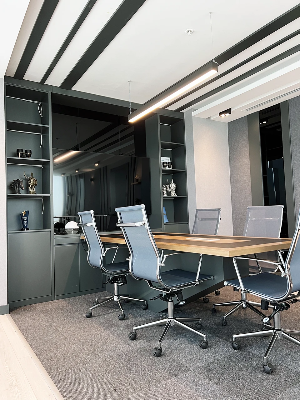Yönetici odası toplantı masası — ahşap masa, krom sandalyeler ve koyu dolap ünitesi