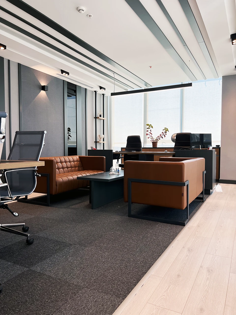 Yönetici odası genel görünüm — çalışma masası, oturma grubu ve halı-parke geçişi