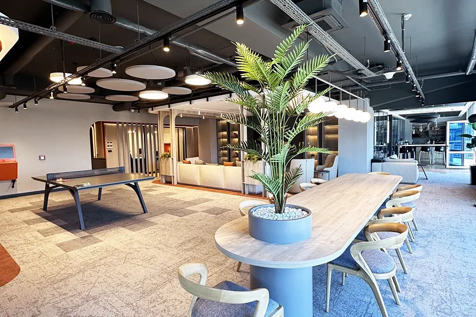 Loop Games Ofis lounge oturma alanı, organik formlu ahşap tavan yapısı, L koltuk, beyaz berjer ve TV ünitesi