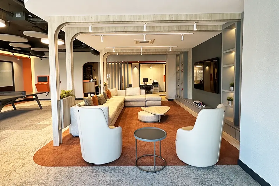 Loop Games Ofis mutfak sosyal alan detayı, gri kumaş sandalyeler, bitki saksısı, turuncu mutfak arka planı