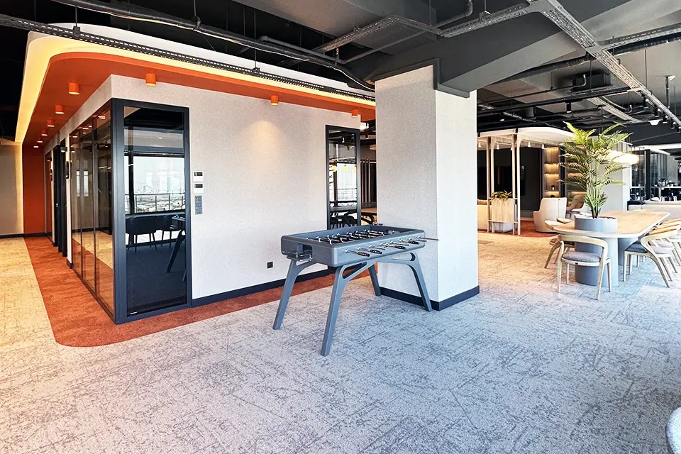 Loop Games Ofis ortak alan, modern langırt masası, cam bölme toplantı odaları, turuncu tavan vurgusu ve halı kaplama