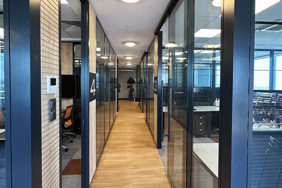 Loop Games Ofis teknolojik koridor, turuncu tavan vurgusu, numaralı cam ofis odaları ve halı kaplama perspektif