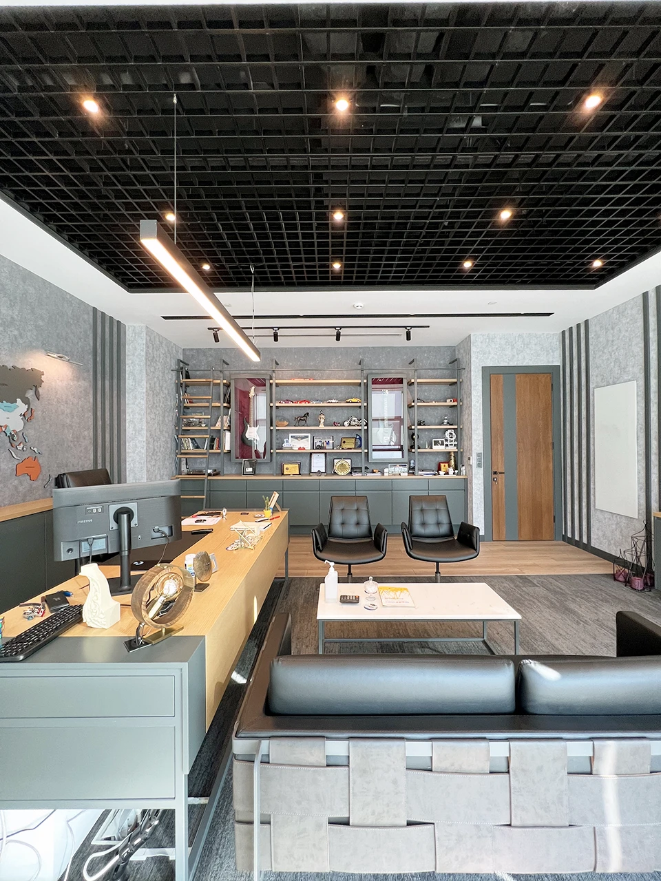 Yönetici ofisi detay — vitrin ünitesi, deri mobilyalar ve özel aydınlatma