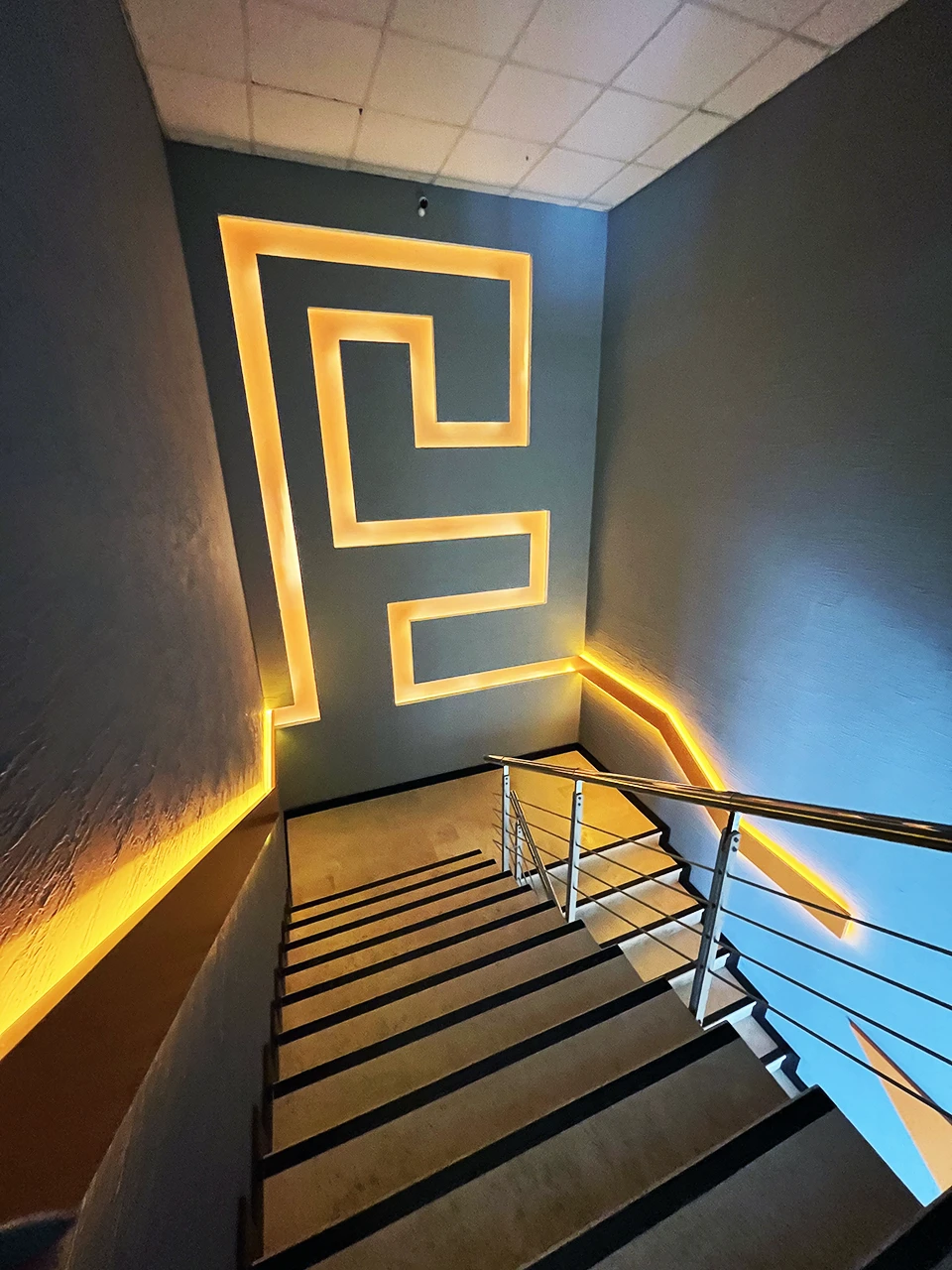 Panteon Ofis LED aydınlatmalı merdiven, Grek meander motifli duvar paneli, gizli LED şerit aydınlatma ve paslanmaz çelik korkuluk