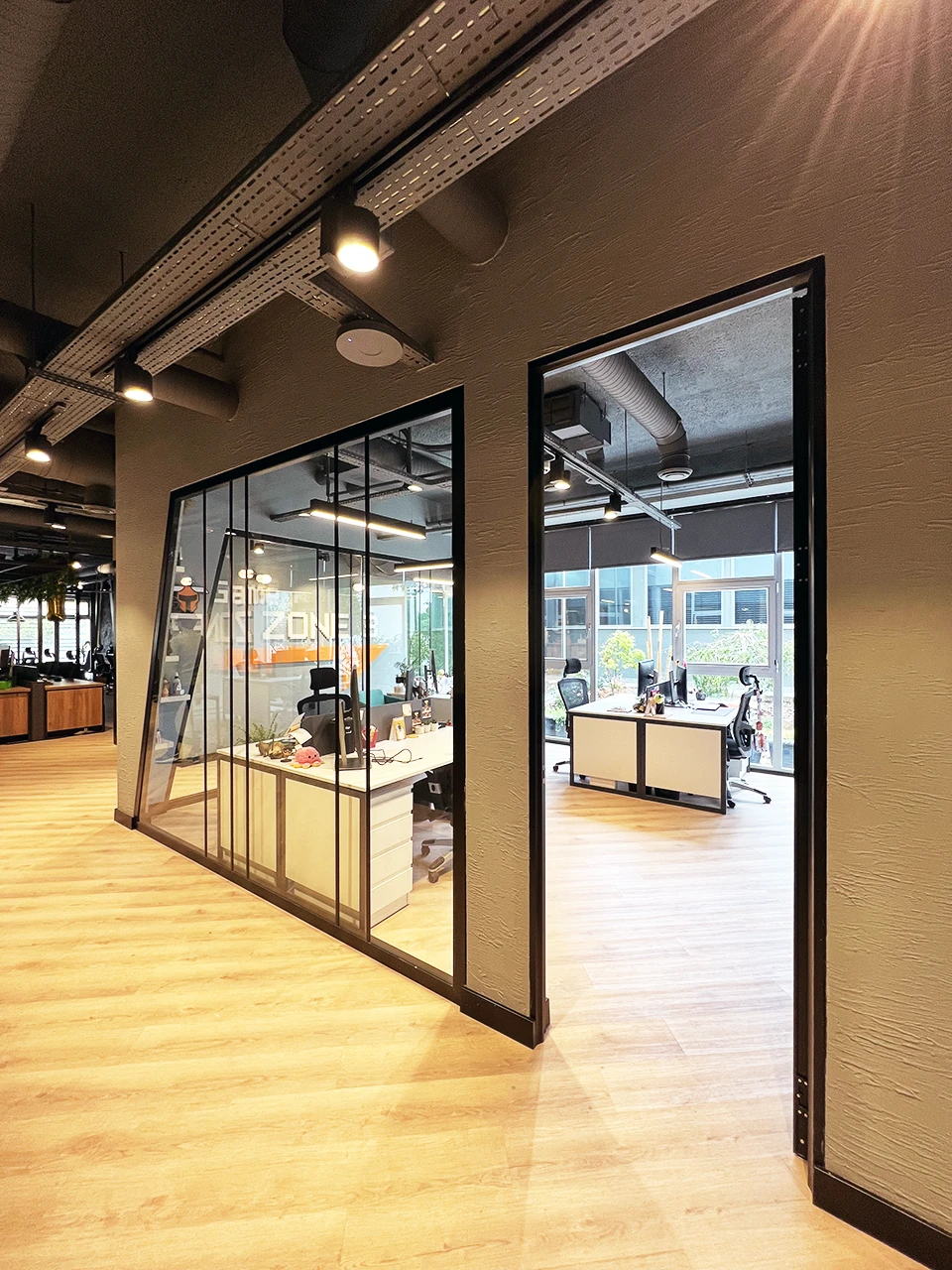 Panteon Ofis giriş holü, cam bölme ofis odaları, Game Zone yazısı, bahçe manzaralı çalışma alanı ve endüstriyel koridor