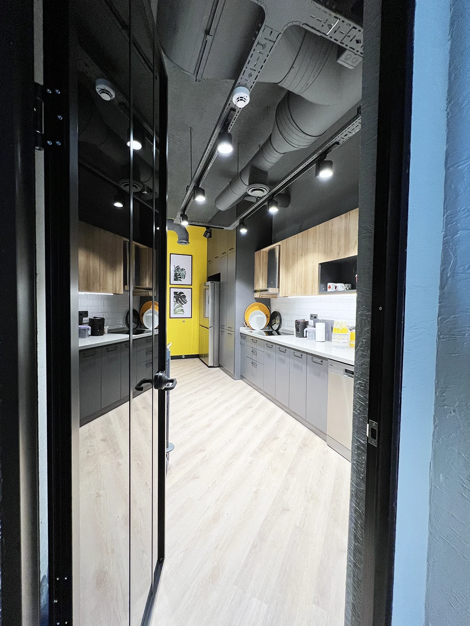 Panteon Ofis mutfak tasarımı, gri alt dolap, ahşap üst dolap, beyaz metro fayans, sarı vurgu duvarı ve endüstriyel tavan